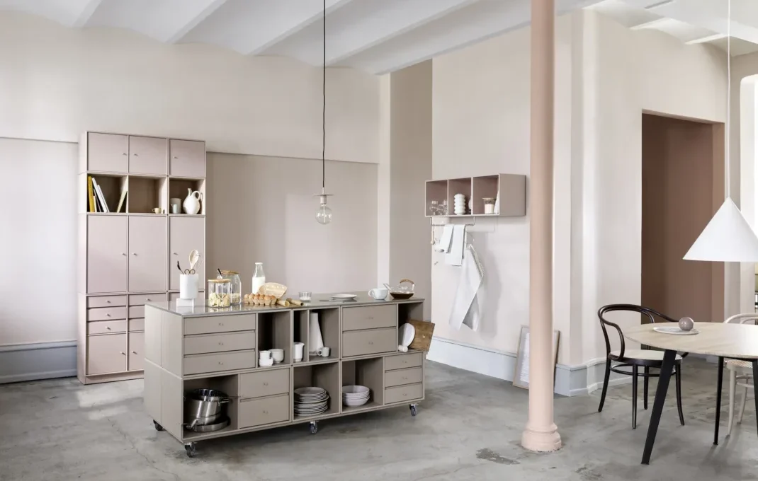 © Montana – Modulares Möbelsystem in Truffle und Mushroom Modulares Montana Möbelsystem in Truffle und Mushroom mit Kücheninsel, Stauraum und Regalelementen in einem hellen Wohnraum